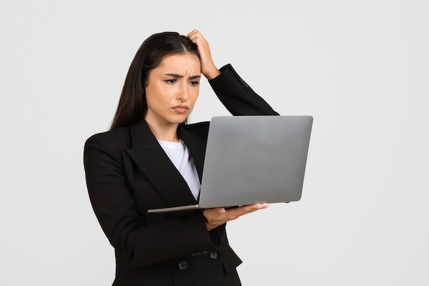 Worried businesswoman looking at laptop and touching head