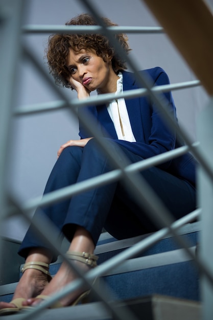 Worried businesswoman sitting on steps at conference centre