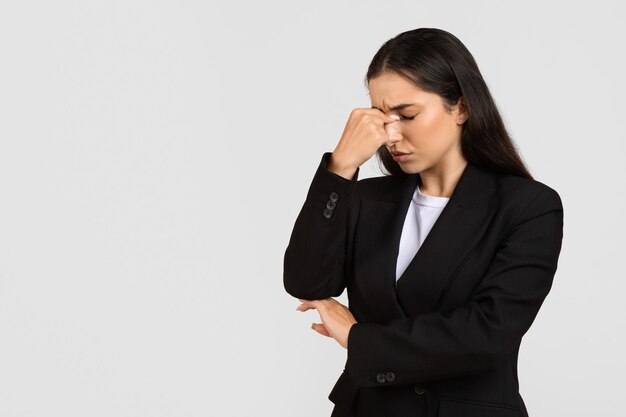 Worried businesswoman with hand on bridge of nose eyes closed
