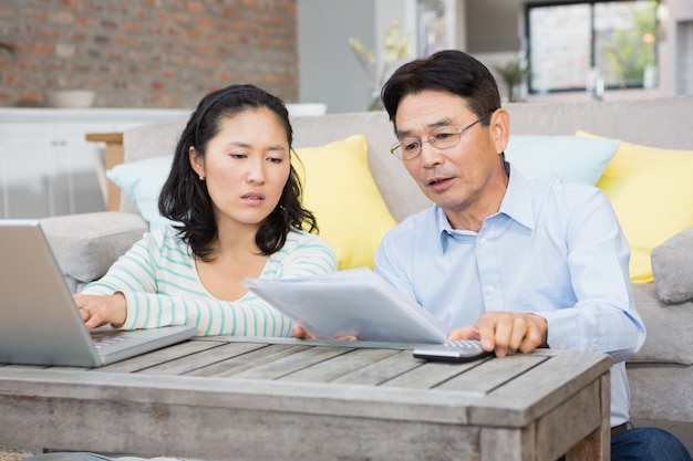 Worried couple checking bills in the living room