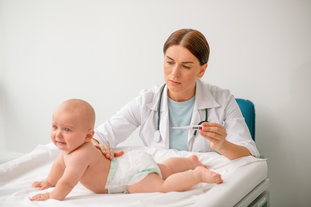 Worried doctor preparing to take a newborn temperature