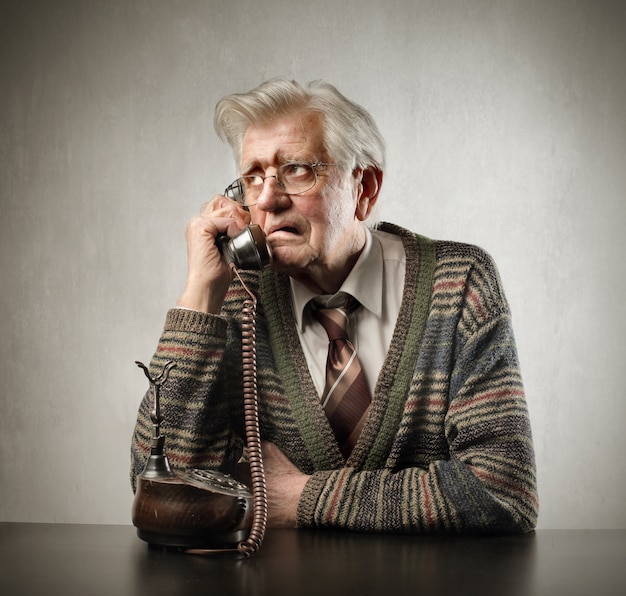 Foto uomo anziano preoccupato che parla su un telefono classico