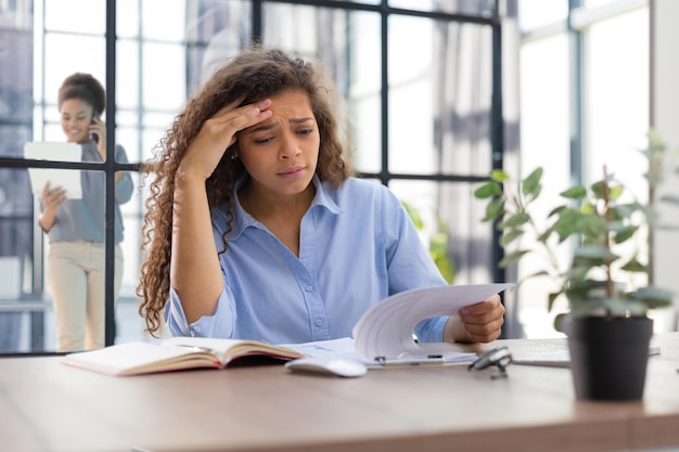 Imprenditrice frustrata preoccupata scioccata da cattive notizie donna d'affari stressata turbata da problemi finanziari il collega è sullo sfondo