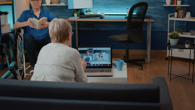 Worried grandma using video conference with medic and child for remote conversation on laptop. Senior woman talking to doctor and little girl on online video call for telehealth.