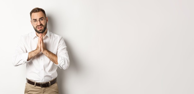 Worried man asking for help begging for favour standing over white background