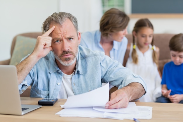 Worried man calculating bills on the laptop in living room