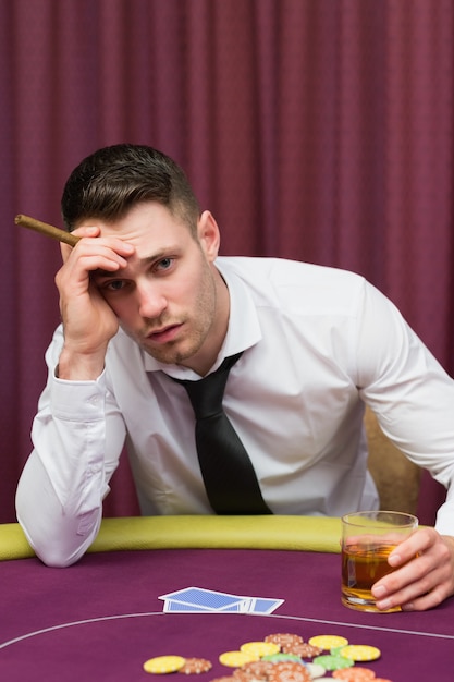 Worried man holding a cigar at poke at table