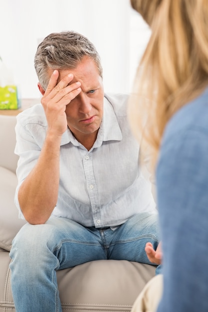 Worried man sitting on couch and talking to therapist 