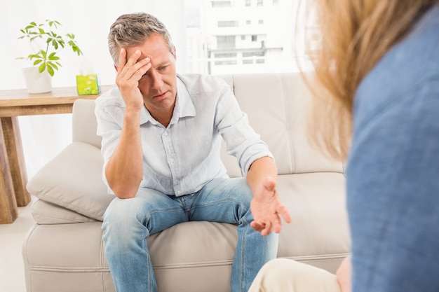 Worried man sitting on couch and talking to therapist 