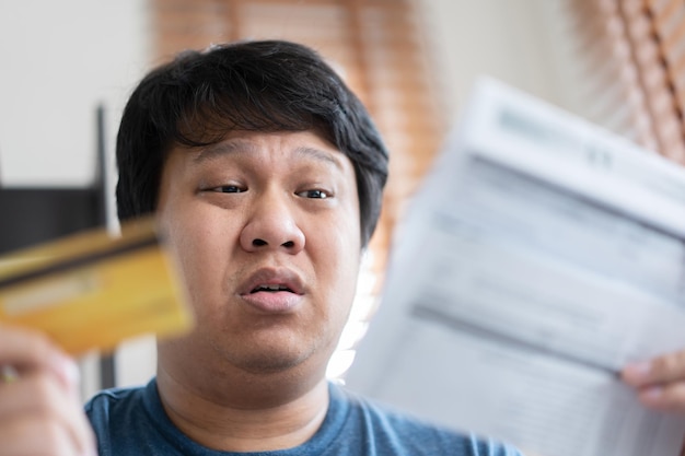 Worried man surprised face with bills total amount