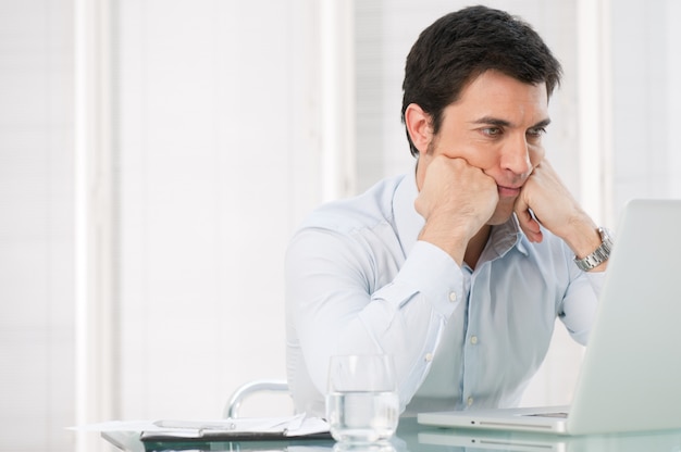 Worried pensive business man watching at his laptop at office