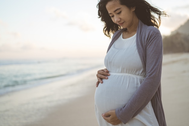 Photo worried pregnant woman stands on the beach