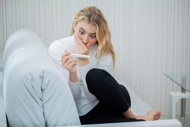 Donna triste preoccupata che esamina un test di gravidanza dopo il risultato.