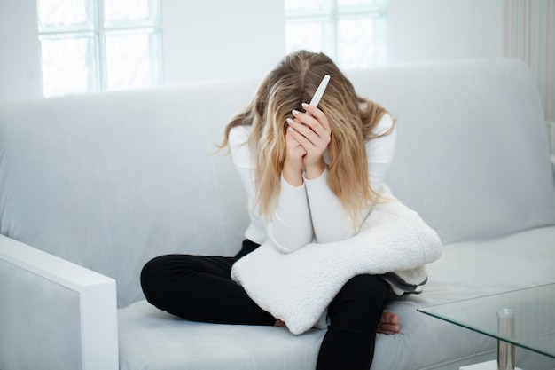 Foto donna triste preoccupata che esamina un test di gravidanza dopo il risultato.