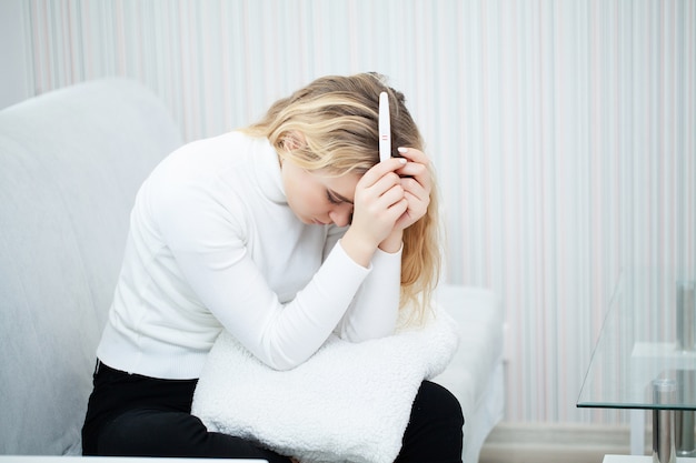 Photo worried sad woman looking at a pregnancy test after result