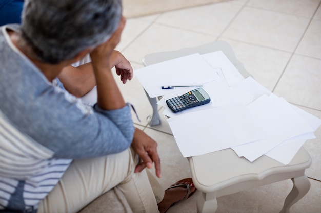 Worried senior couple checking bills in living room