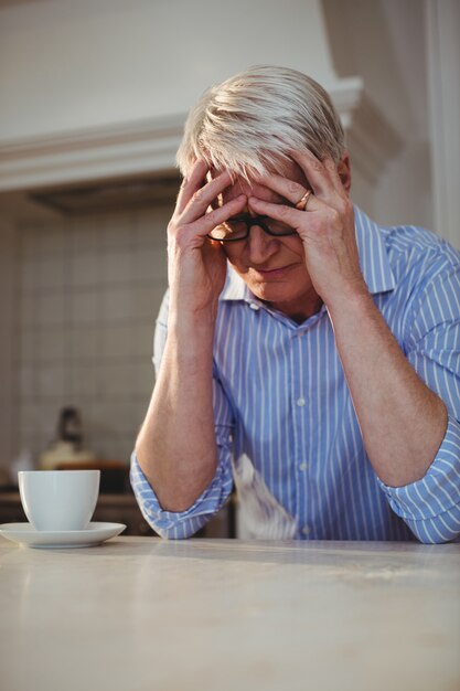 一杯のコーヒーと座っている心配している年配の男性