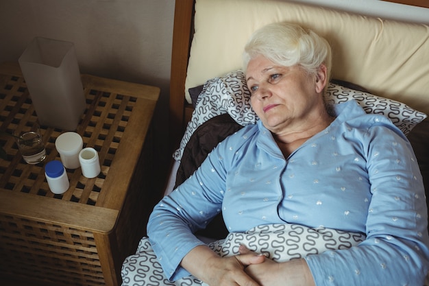 Фото Потревоженная старшая женщина ослабляя на кровати