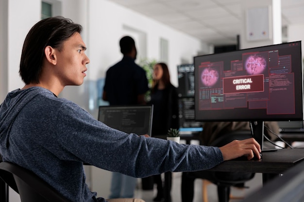 Worried software developer having web server hacked, looking at
critical error on computer screen in programming office. asian web
developer trying to solve hacking problem, firewall security.