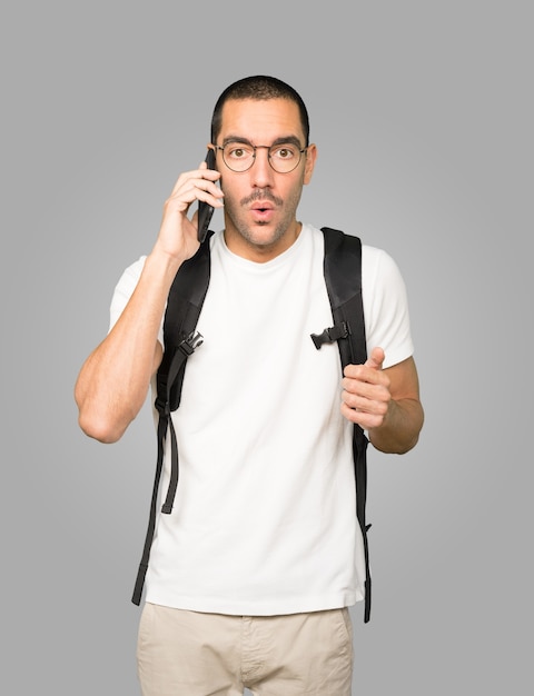 Worried student pointing up and using his mobile phone