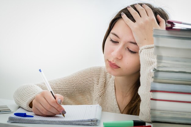 Foto ragazza adolescente preoccupata che scrive su un libro sullo sfondo bianco