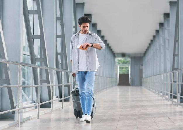 Worried tourist checking time on watch going in airport walkway