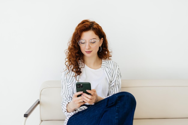 Photo worried woman look on screen of smartphone touch palm on cheek sit on comfort cozy sofa or couch in modern light interior