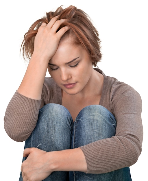 Worried woman sitting holding knees with arm on background