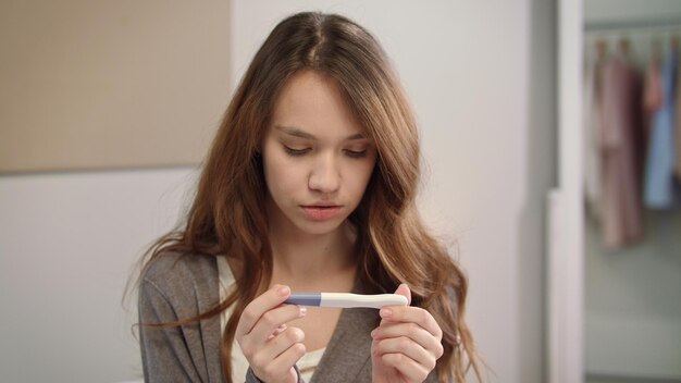 Worried woman waiting pregnant test results Girl looking at pregnancy test