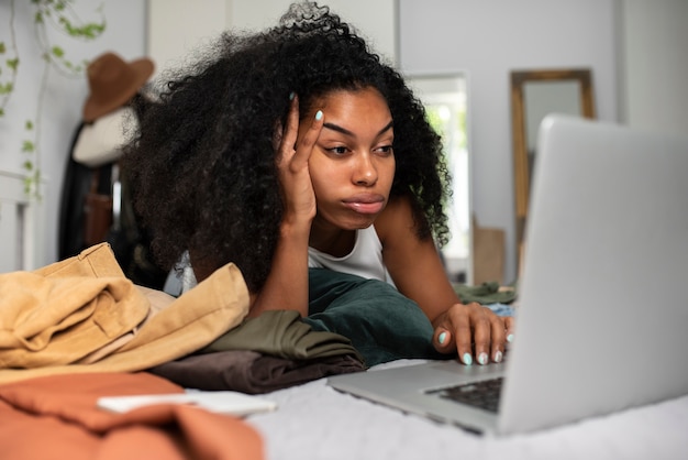 Foto donna preoccupata con il computer portatile nella vista laterale del letto