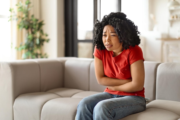 Una giovane donna nera preoccupata seduta con le braccia incrociate e dall'aspetto preoccupato