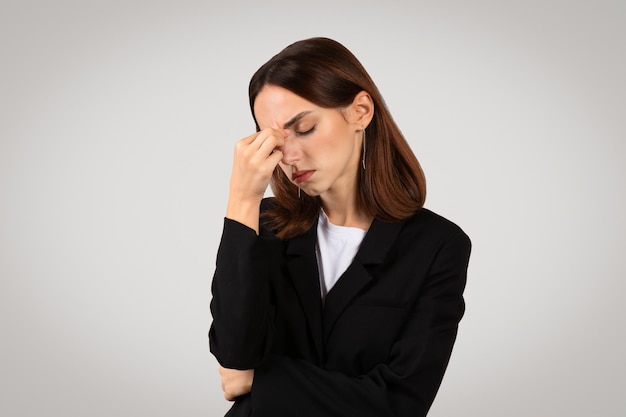 Worried young businesswoman in a black suit holding her forehead