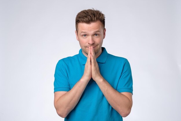 Worried young caucasian man put hands together ask for help forgiveness in prayer gesture