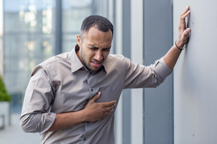 Photo worried young man clutching chest in pain suffering from heart attack health emergency concept