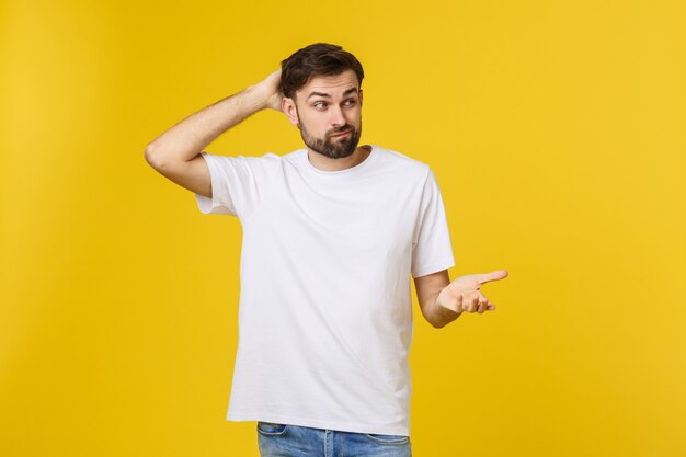 立っている心配している若い男が黄色の壁に分離します。