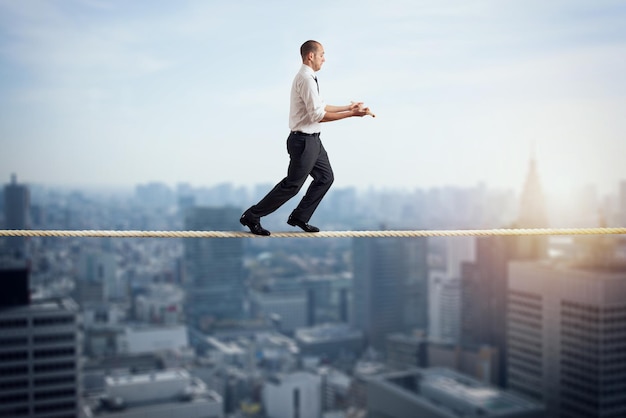 Worry man in balance walking on a rope over a city