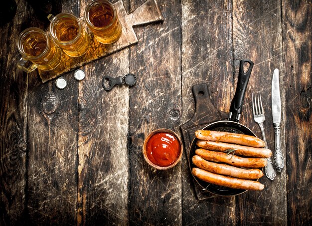 Worsten met koud bier en saus op houten tafel.