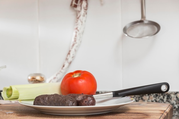 Worstjes op een bord naast een steelpan een vuurstaaf aan de muur