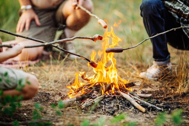 Worstjes roosteren boven een vuurtje in het bos