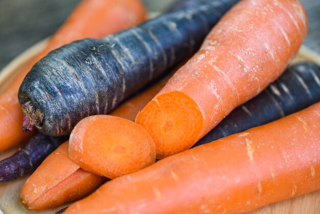 Wortel en paarse wortel op dienblad, verse wortel voor vegetarisch koken op houten tafel in de keuken