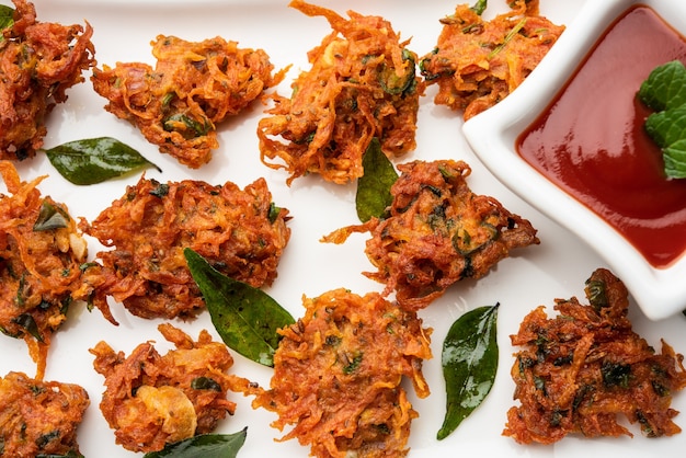 Wortelbeignets of Gajar ke pakore of pakode of bajji of bhaji, Indiase snack geserveerd in een bord met tomatenketchup