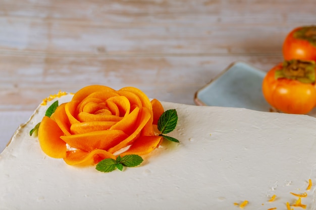 Worteltaart bedekt met roomkaasglazuur en versierd met gesneden persimmon