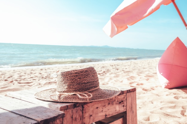 非常に寒い休日に海のそばのテーブルに置かれた編まれた帽子。夏休みと旅行のコンセプト