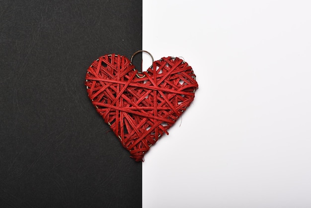 Woven heart ornament in red colour. Valentines day and love concept. Handmade decoration on black and white background.