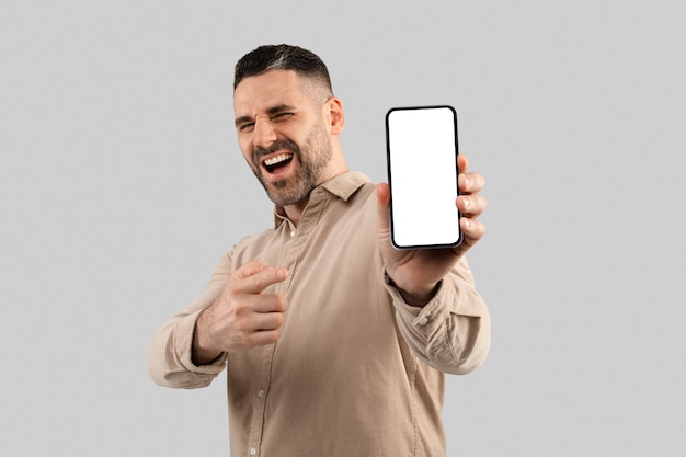 Wow cool website excited middle aged man pointing finger at smartphone with blank screen on light