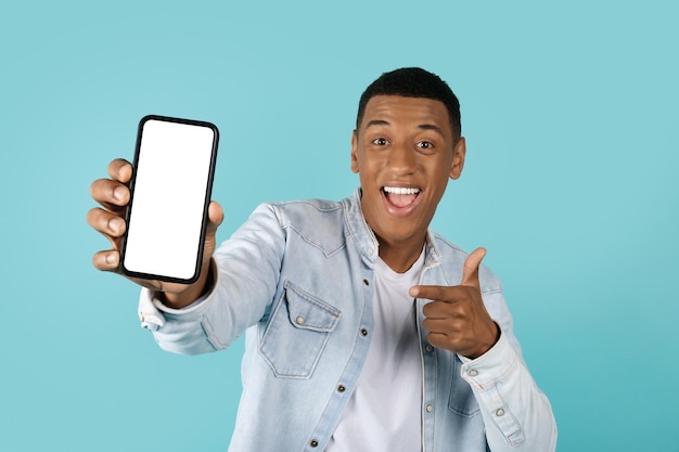 Wow coole website Tevreden jonge afro-amerikaanse man wijzende vinger naar smartphone met leeg scherm