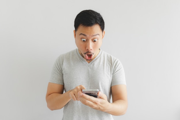 Wow face of man in grey t-shirt get surprised on the smartphone.