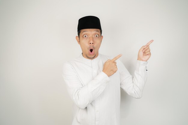 Wow face shocked expression Asian Muslim man wearing Arab costume pointing hand finger at