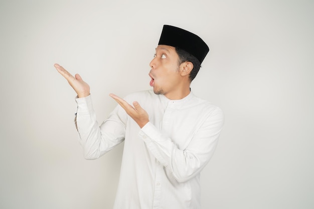 Foto wow faccia espressione scioccata uomo musulmano asiatico che indossa costume arabo puntando il dito della mano