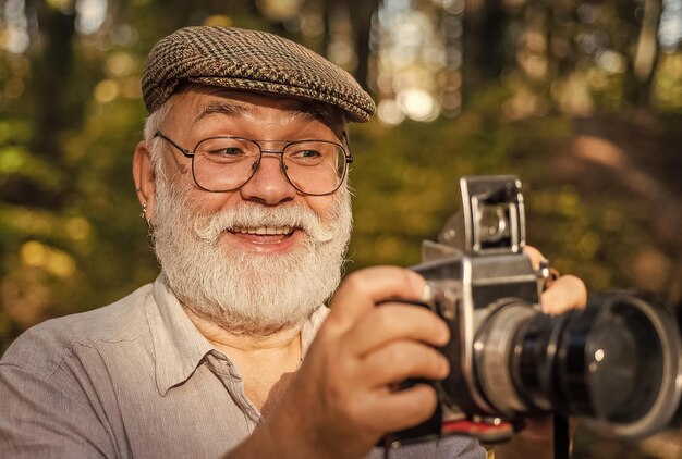 Photo wow i like it capture memories from trip portrait of man holding vintage camera mature man in glasses selective focus confident photographer closeup portrait of man holding vintage photo camera